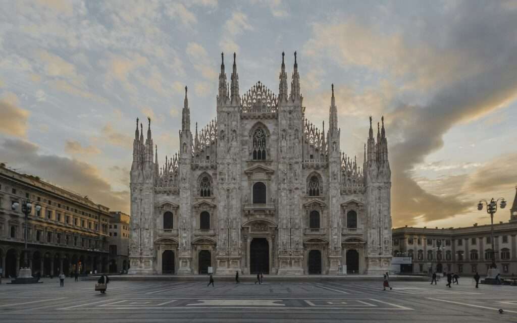 The marble facade of Milan's Duomo at dawn with an almost empty piazza